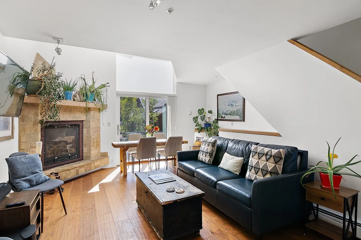 A cozy living space featuring a fireplace, comfortable sofa, and dining table surrounded by lush indoor plants. The room exudes warmth and relaxation, ideal for hosting games, socializing, or simply unwinding after outdoor adventures.