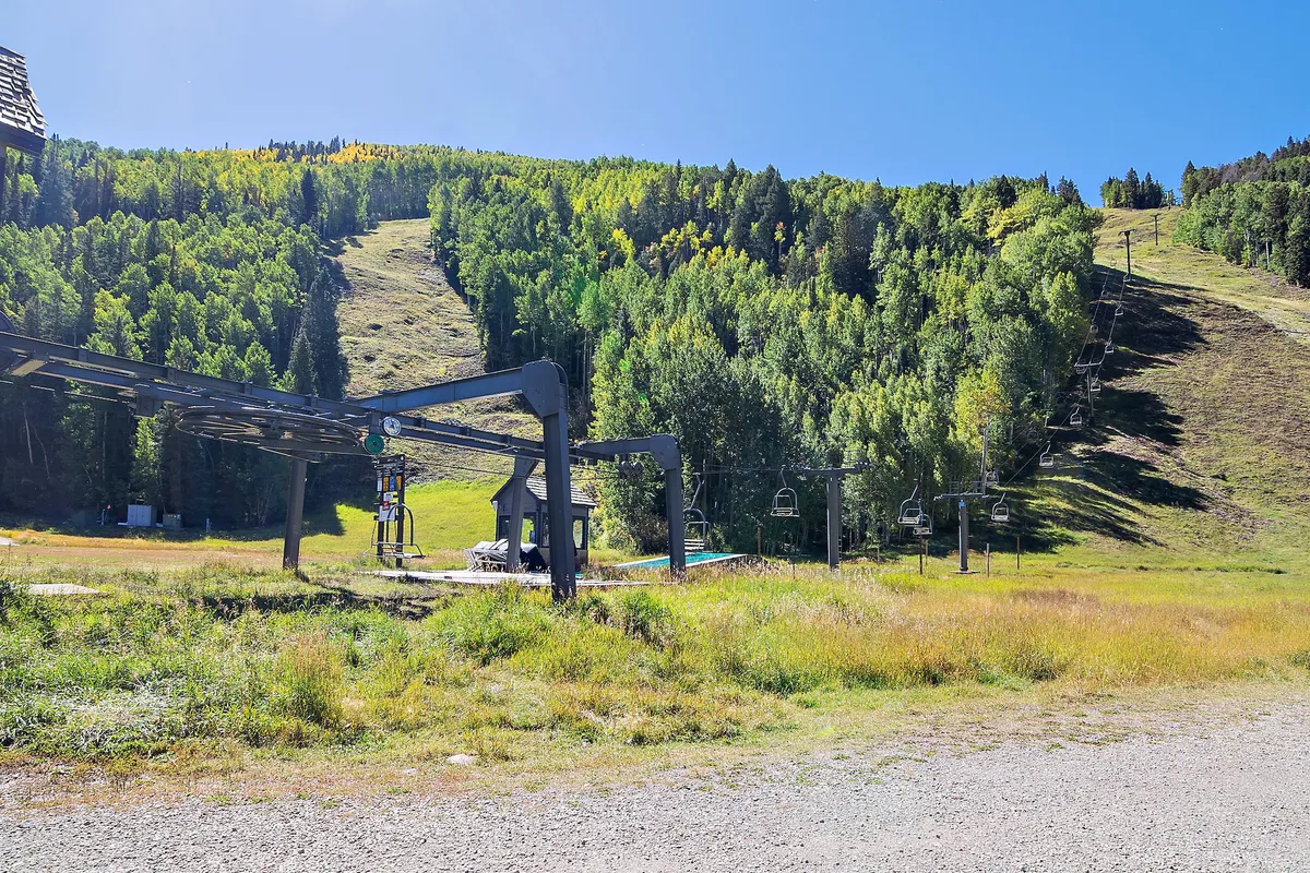 This exterior image captures a ski lift ascending in front of a stunning mountain backdrop, with lush greenery at the base. It highlights the sense of adventure and direct access to outdoor activities available just outside the townhouse.