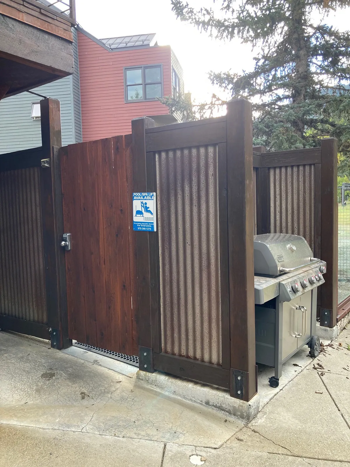 A casual BBQ area featuring a grill, wooden fence, and friendly signage, ideal for outdoor cooking and summer gatherings. The space feels inviting and functional, encouraging communal experiences and fun cooking sessions.