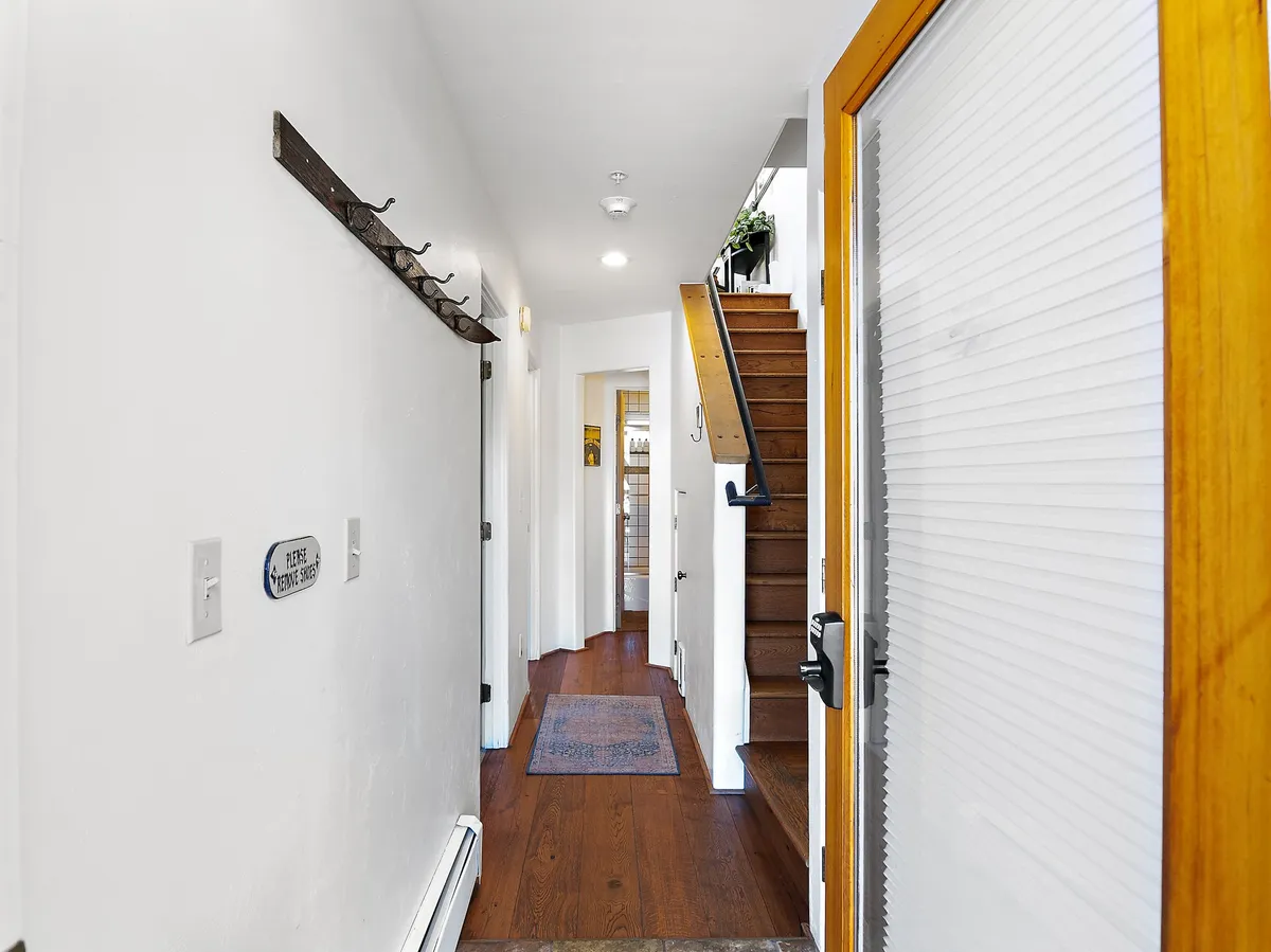 A bright, inviting entrance hallway with a staircase and a welcoming rug, signaling effortless home access and transitions between spaces. The area is functional for storing coats and gear, especially after a day on the slopes.