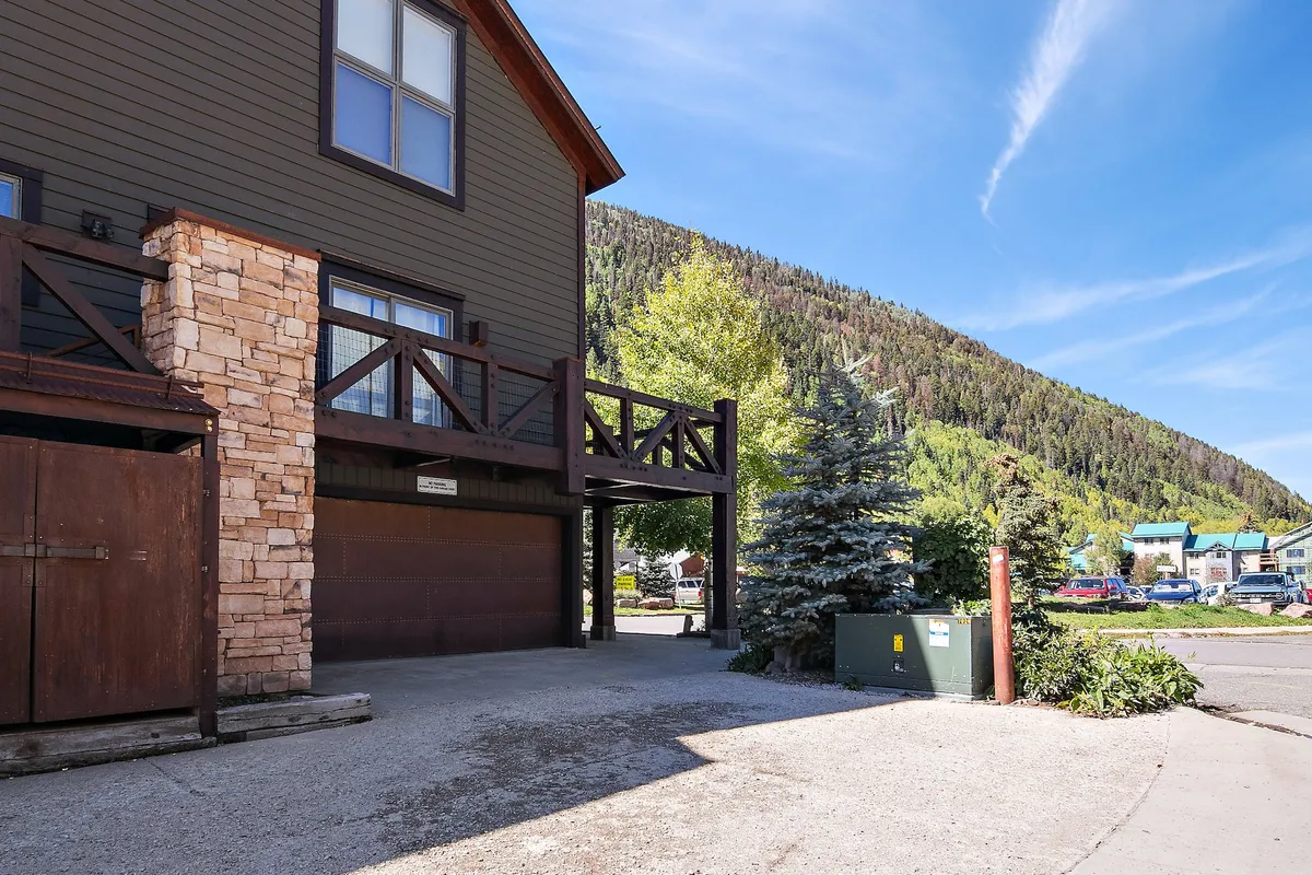 A cozy wooden balcony overlooking lush greenery and a majestic mountain backdrop. The stone facade and inviting atmosphere evoke warmth and comfort, suggesting possibilities for both lively gatherings and tranquil solitude as described in the section.